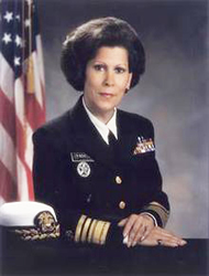 A woman in military uniform sitting at a desk.