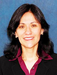 A woman with long black hair wearing a suit.