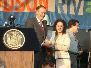 A woman is holding her award while standing next to a man.